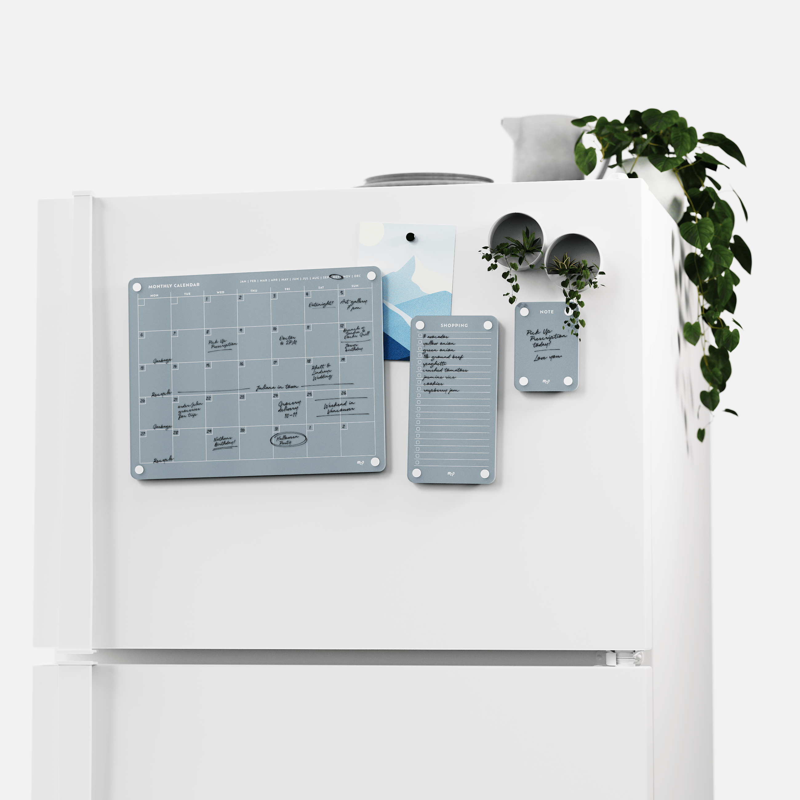 White fridge with the Slate grey monthly calendar, shopping list and note board set, plants on top